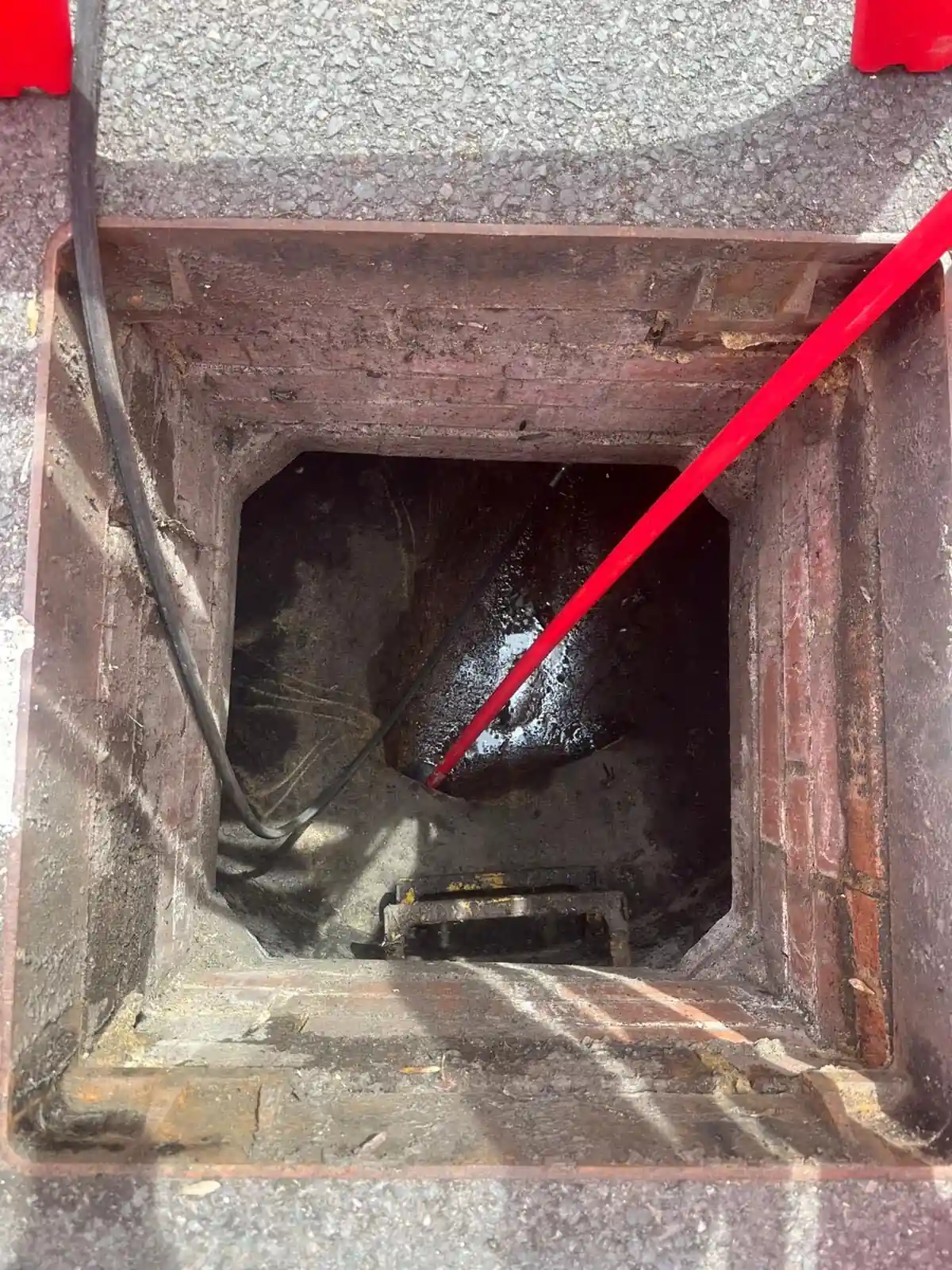 Drain rod and camera cable in a surface water drainage chamber in a commercial car park, Berkshire